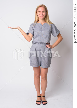 Full body shot of happy young blonde woman showing something Full body shot of happy young blonde woman showing something 58814417