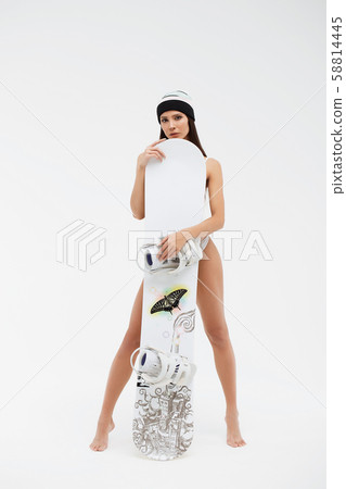 Barefoot woman standing behind snowboard 58814445