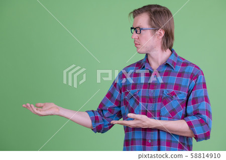 Profile view of young handsome hipster man with eyeglasses showing something 58814910