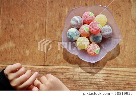 玻璃盤上放著彩色硬糖的小女孩的手 玻璃盤上放著彩色硬糖的小女孩的手 58819933