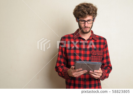 Young bearded hipster man with curly hair using digital tablet 58823805