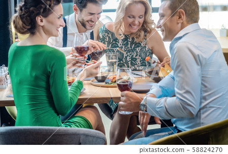 Friends in a restaurant having a jolly good time enjoying the food 58824270
