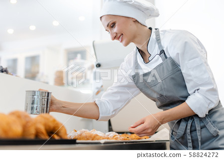 Confectioner woman powdering cocoa on sweet bread 58824272