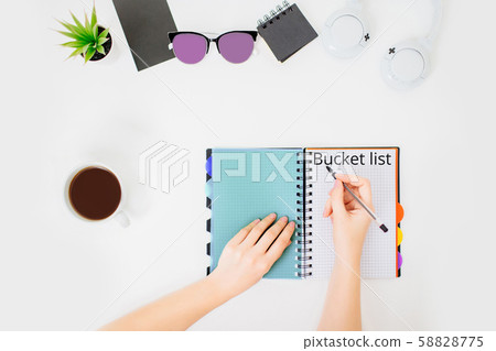 Flatlay with female hands writing bucket list. Flatlay with female hands writing bucket list. 58828775
