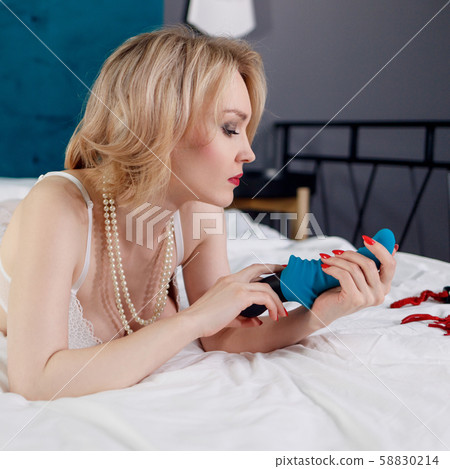 Sexy woman in white lingerie holds blue sex rubber toy. Sexy woman in white lingerie holds blue sex rubber toy. 58830214