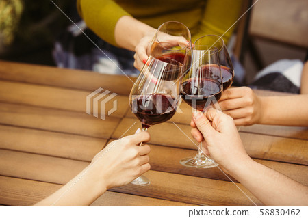 People clinking glasses with wine on the summer terrace of cafe or restaurant. Close up shot 58830462