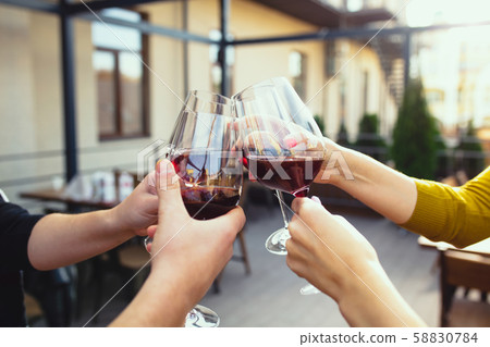 People clinking glasses with wine on the summer terrace of cafe or restaurant. Close up shot People clinking glasses with wine on the summer terrace of cafe or restaurant. Close up shot 58830784