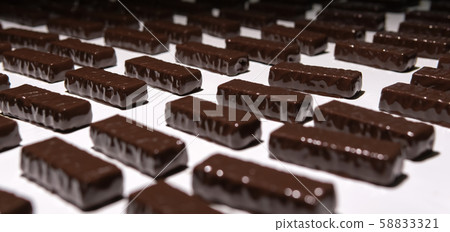 chocolate candies on the conveyor of a 58833321