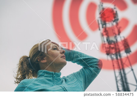 Woman is holding her head near the 5G BTS 58834475