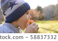 A child in the autumn Park on a picnic. He eats a juicy red Apple. Close up face 58837332