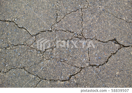 Cracked old paved road surface 58839507