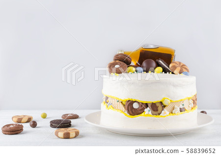funny cake with a bottle of alcohol, candy and cookies on gray background 58839652