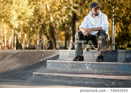 Man in skatepark with skateboard on warm autumn day 58842683