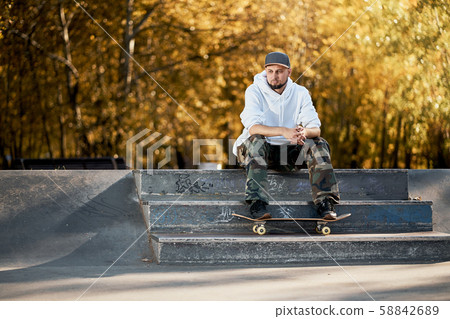 Man in skatepark with skateboard on warm autumn day Man in skatepark with skateboard on warm autumn day 58842689