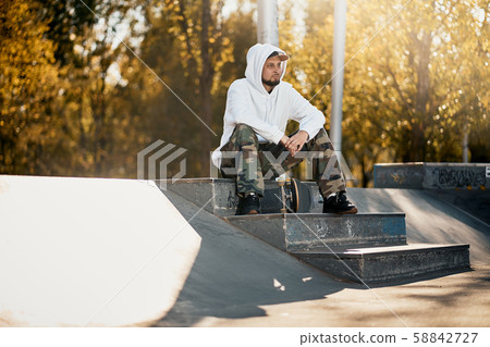 Man in skatepark with skateboard on warm autumn day Man in skatepark with skateboard on warm autumn day 58842727