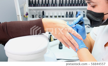 Manicurist paints nails to a client in a beauty salon. Gel polish. Lacquer. Manicure. Nail extension Manicurist paints nails to a client in a beauty salon. Gel polish. Lacquer. Manicure. Nail extension 58844557