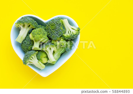 Fresh broccoli in a heart shaped bowl on yellow Fresh broccoli in a heart shaped bowl on yellow 58844893