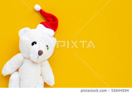 Toy bear wearing a santa hat on yellow background. 58844894
