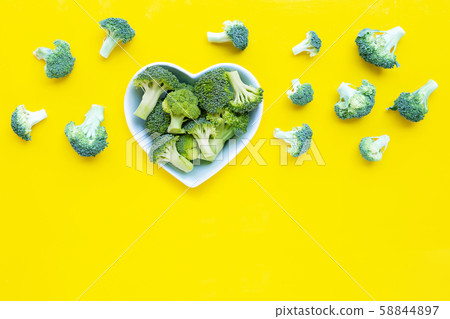 Fresh broccoli with a heart shaped bowl on yellow Fresh broccoli with a heart shaped bowl on yellow 58844897