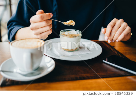 Woman in a cafe eating a dessert Woman in a cafe eating a dessert 58845329