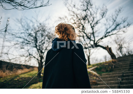 View from the back of a woman in a black coat View from the back of a woman in a black coat 58845330