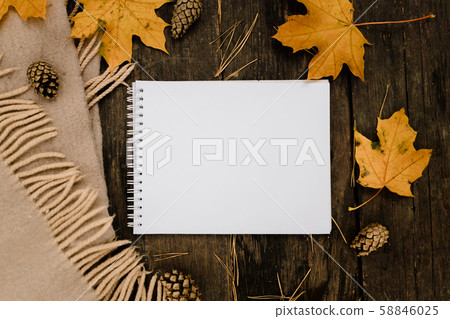 White blank notebook and pen on a dark background with a scarf, plaid and a cup, autumn yellow White blank notebook and pen on a dark background with a scarf, plaid and a cup, autumn yellow 58846025