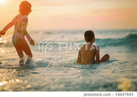 sister and brother on the beach at sunset, rear view. sister and brother on the beach at sunset, rear view. 58847685