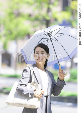 Business woman pointing a parasol Business woman pointing a parasol 58850427