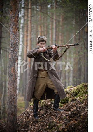 A soldier of World War II is holding the rifle in his hands and aiming 58853709