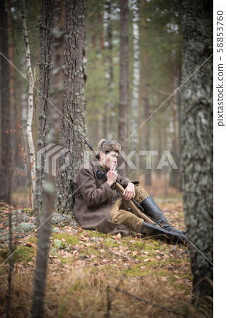A soldier of World War II is sitting in the forest and smoking 58853760