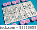 Color contact lenses in blisters and contact lens cases on blue background 58856655