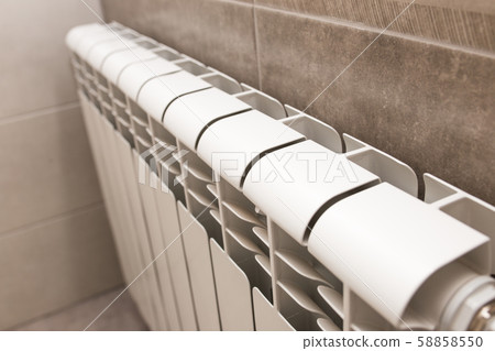 White radiator in the bathroom close-up. Heating. Tiled gray wall. 58858550