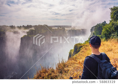 Tourist looks at the Victoria Falls on Zambezi River in Zimbabwe 58863319