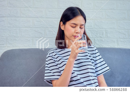 Young Asian woman drinking water in glass on sofa 58866288