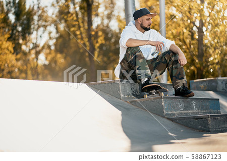 Man in skatepark with skateboard on warm autumn day Man in skatepark with skateboard on warm autumn day 58867123