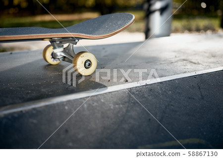 Closeup of skateboard in concrete skatepark on warm day Closeup of skateboard in concrete skatepark on warm day 58867130