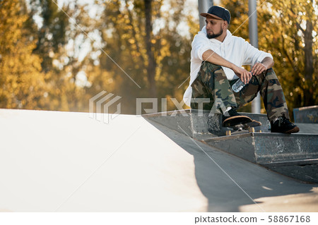 Man in skatepark with skateboard on warm autumn day Man in skatepark with skateboard on warm autumn day 58867168