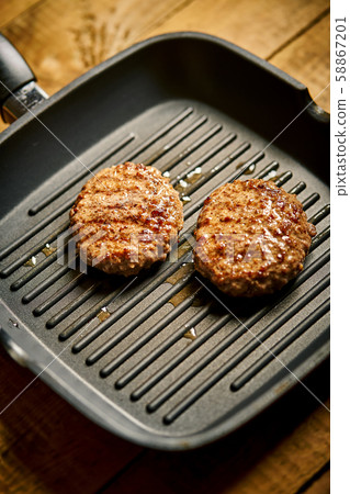 Closeup of juicy burgers fried on black grill pan 58867201