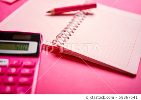 Closeup of calculator and notebook with pencil on pink desk 58867541