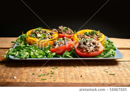 Peppers stuffed with champignons with lettuce on wooden table Peppers stuffed with champignons with lettuce on wooden table 58867885