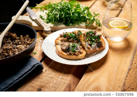 Toasts with mushrooms on white plate on wooden kitchen table Toasts with mushrooms on white plate on wooden kitchen table 58867896