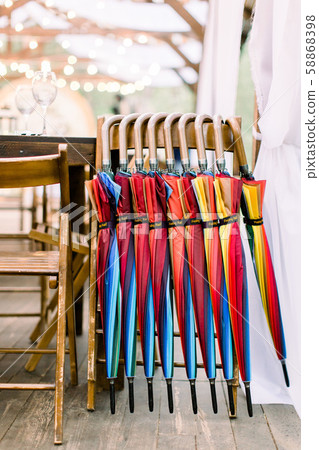 Set of colorful umbrellas on the wooden chair for guests of the wedding ceremony outdoors. Wedding Set of colorful umbrellas on the wooden chair for guests of the wedding ceremony outdoors. Wedding 58868398