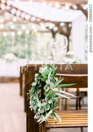 Hands making wedding wreath from eucalypthus and flowers hanging on wooden chair. Wedding, rustic Hands making wedding wreath from eucalypthus and flowers hanging on wooden chair. Wedding, rustic 58868421