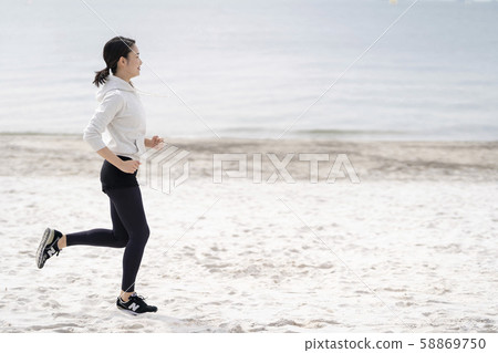 Woman running on sandy beach 58869750