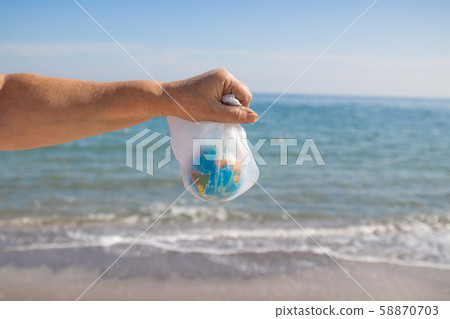 Woman hands a plastic bag and planet Earth on sea 58870703