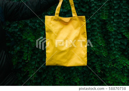 Handmade shopping bag on green plant background. Handmade shopping bag on green plant background. 58870738