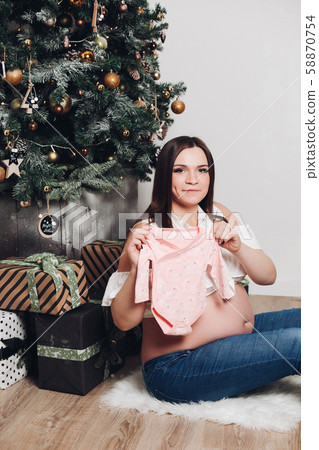 Pregnant woman posing with baby bodysuit. Happy 58870754