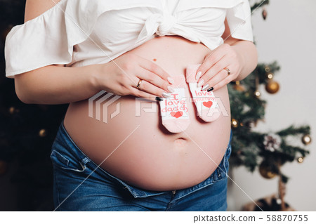 Woman with naked pregnant belly holding little 58870755