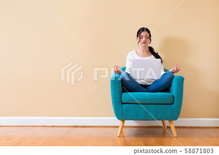 Young woman with laptop in a meditation pose 58871803
