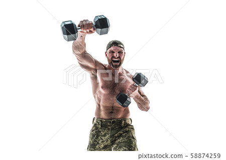 Muscular athlete bodybuilder man in camouflage pants with a naked torso punching with dumbbells like 58874259